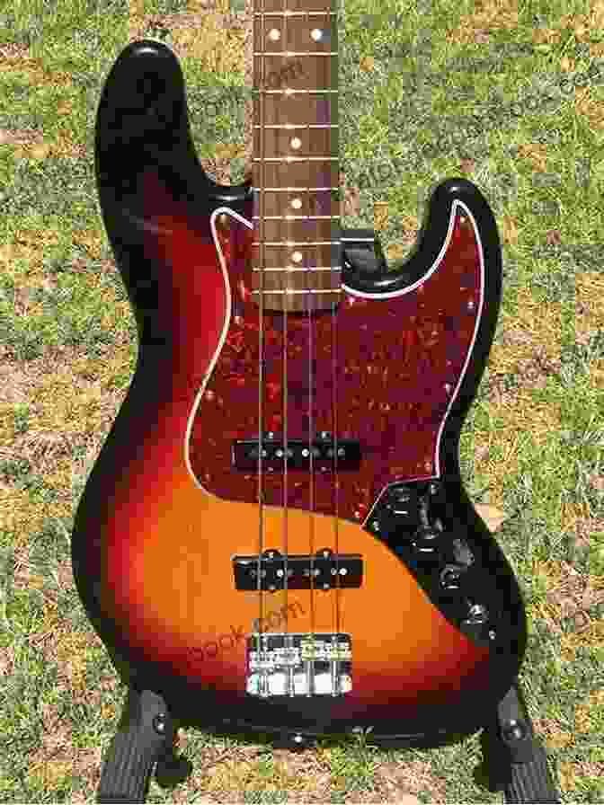 A Blues Bass Guitar With A Sunburst Finish And A Maple Fretboard. The Bass Is Strung With Roundwound Strings And Has A Single Pickup. The Bass Is Being Played By A Man With A Goatee And A Baseball Cap. The Man Is Wearing A Black T Shirt And Jeans. The Man Is Playing The Bass In A Dimly Lit Room With A Brick Wall In The Background. The Essential Guide To Blues Bass Guitar: Learn Blues Bass Guitar With A Simple Easy To Understand System Designed Especially For Beginner To Intermediate Intermediate Bass Guitar Training 1)